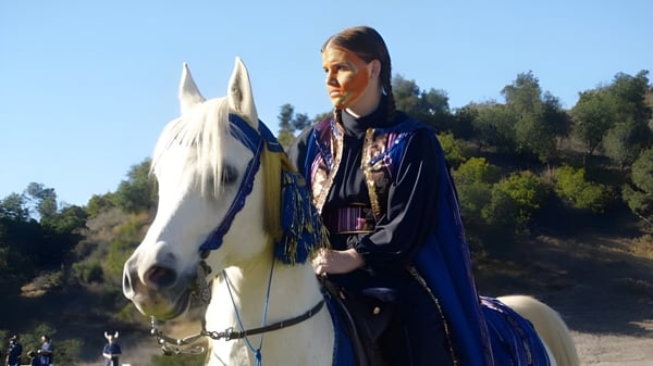 Una persona está al lado de un caballo blanco en el terreno de la Villanova Preparatory School.