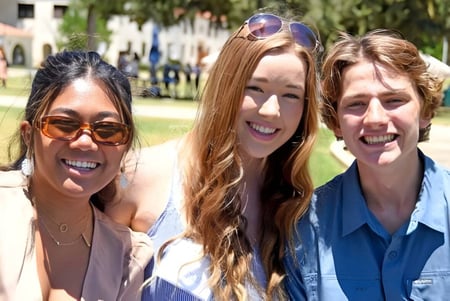 Tres estudiantes están juntas en el campus de la Villanova Preparatory School al aire libre frente a árboles y edificios.