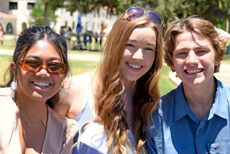 Tres estudiantes están juntas en el campus de la Villanova Preparatory School al aire libre frente a árboles y edificios.