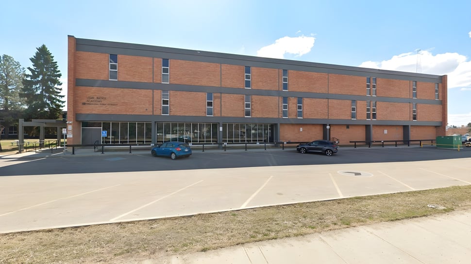 El edificio de ladrillo de varios pisos con diseño moderno de la Vimy Ridge Academy se encuentra frente a un estacionamiento pavimentado y áreas verdes.