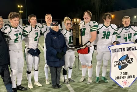 Jugadores de fútbol del Institut Collégial Vincent Massey Collegiate sostienen un trofeo en el campo por la noche.