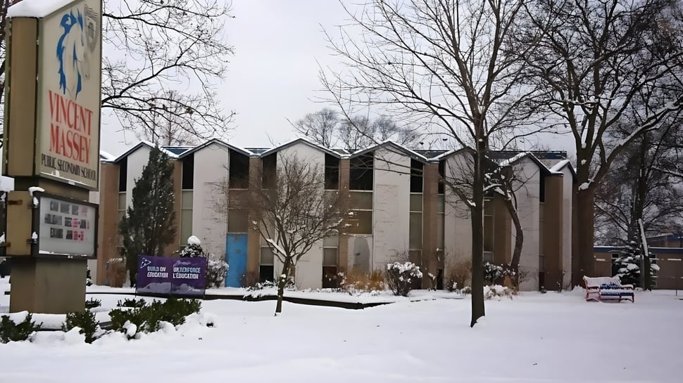 Paisaje cubierto de nieve con edificios de varios pisos y estudiantes en el campus de la Vincent Massey Secondary School en invierno.