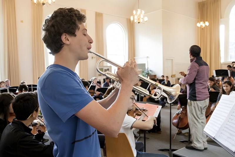 Un estudiante de la Vineridge Academy toca un instrumento de metal en el escenario frente a un gran público en un salón lujoso.