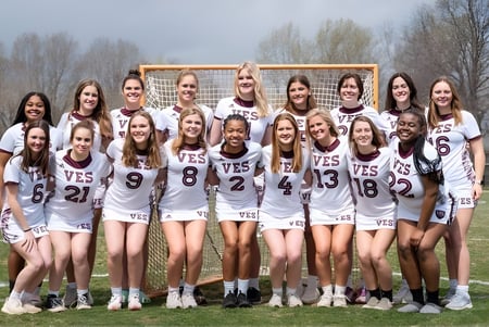 Un grupo de jóvenes estudiantes en uniformes deportivos está reunido en el campo de deportes de la Virginia Episcopal School.