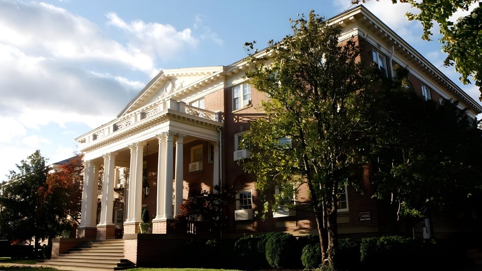 El histórico edificio principal de la Virginia Episcopal School con fachada de columnas rodeado de árboles verdes bajo un cielo azul.