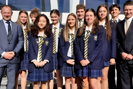 Un grupo de estudiantes de Wakatipu High School posan frente a un edificio moderno con grandes ventanas.