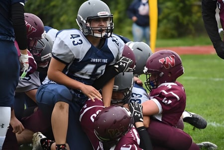 Estudiantes de la Wallaceburg District High School juegan un partido de fútbol americano con tackle en el campo.