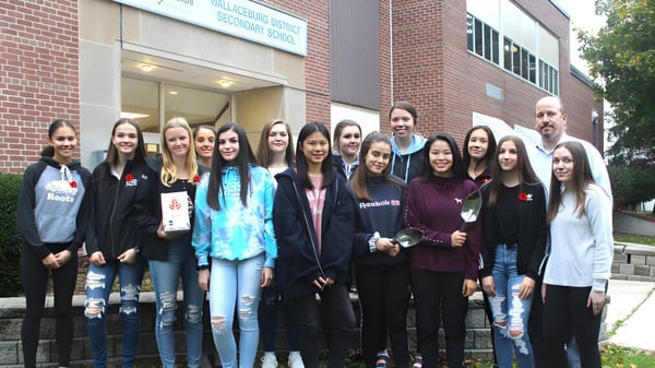 Un grupo de estudiantes se encuentra frente al edificio de ladrillo de la Wallaceburg District High School.