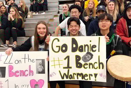 Un grupo de estudiantes de la Walnut Grove Secondary School sostiene carteles y vitorea en un evento.