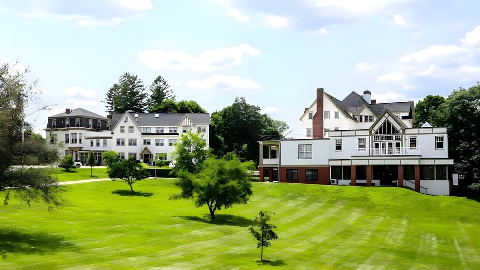 Una pradera verde frente a varios edificios históricos en el campus de la Walnut Hill School for the Arts.