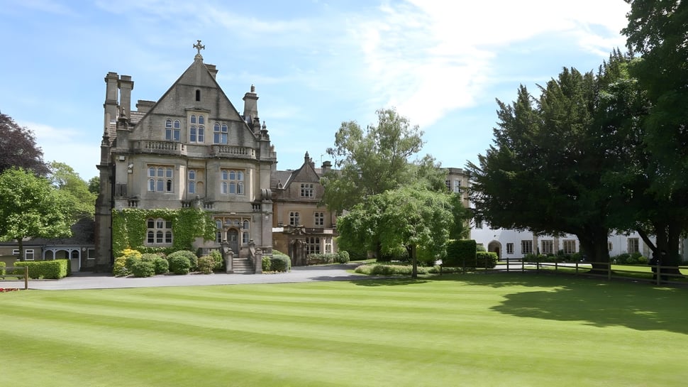 El castillo de Warminster School está rodeado de césped cuidado y setos en un paisaje ajardinado.