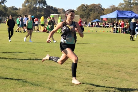 Un estudiante de Warwick Senior High School corre en un campo de hierba durante una competencia deportiva al aire libre.