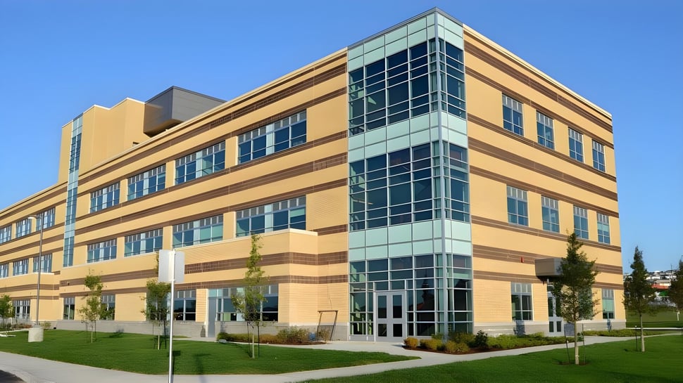 El moderno edificio de varios pisos de la Waterford Valley High School está rodeado de praderas y árboles.