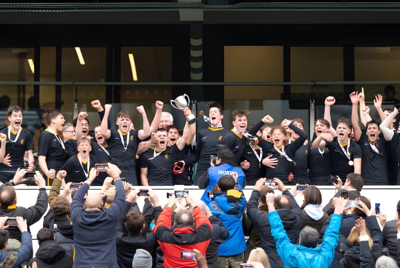 Un grupo de estudiantes en uniformes negros celebra juntos en el campus del Wellington College.