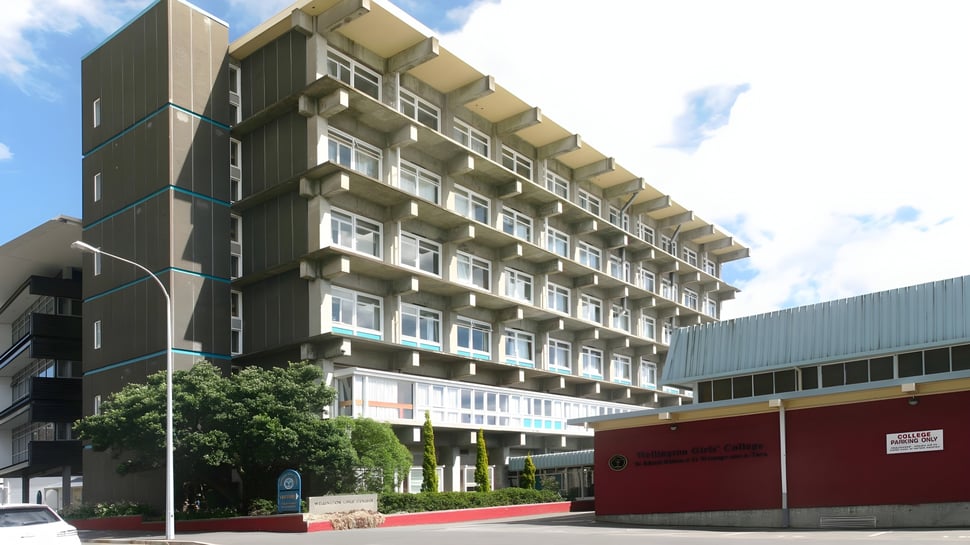El edificio de varios pisos con diseño moderno en el campus del Wellington Girls' College está rodeado de árboles.