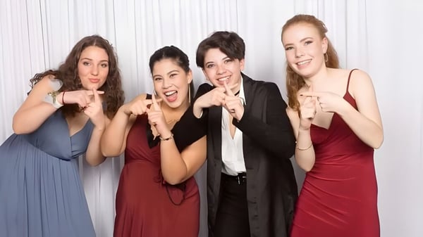 Cuatro mujeres en ropa formal durante una sesión de fotos con fondo blanco en el Wellington Girls' College.
