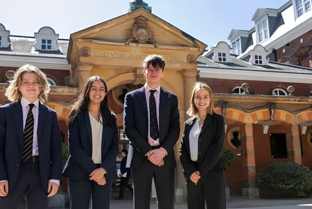 Un grupo de cuatro estudiantes está frente a un edificio histórico en el terreno de la Wellington School.