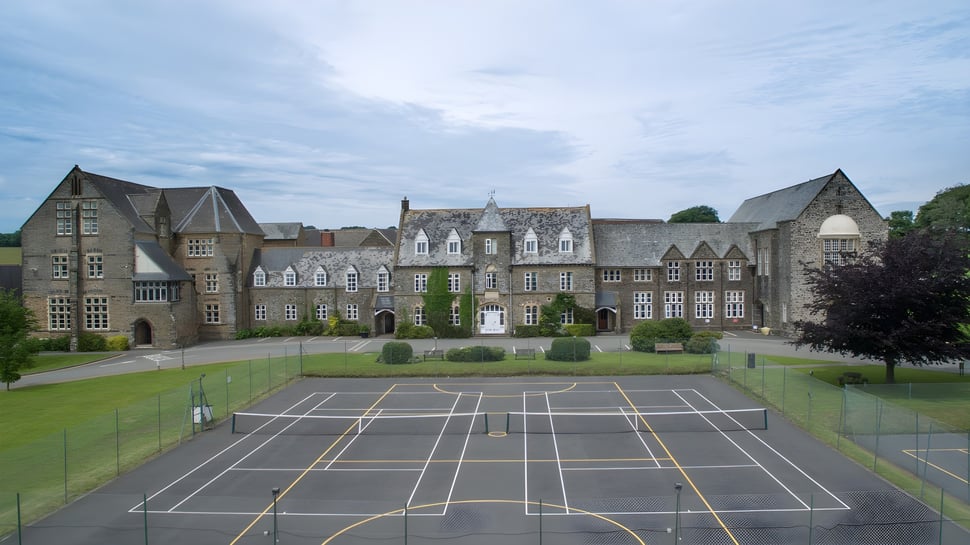 El edificio histórico de la West Buckland School se encuentra detrás de un césped bien cuidado y una cancha de baloncesto.