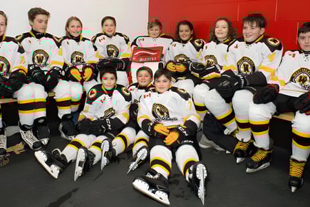 Estudiantes de la West Carleton Secondary School posan juntos en sus uniformes de hockey en una sala de hockey.