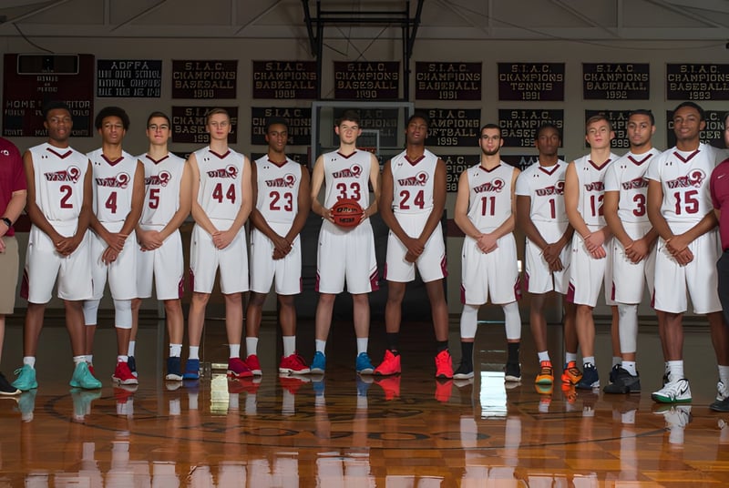 Un grupo de estudiantes de la West Nottingham Academy posan juntos en la cancha de baloncesto con pancartas de fondo.