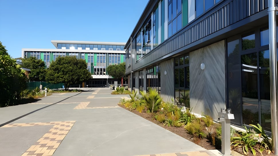 Vista del moderno edificio con fachada de vidrio en el campus del Western Springs College rodeado de un paisaje verde.