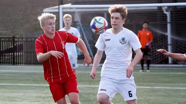 Dos alumnos de la Westlake Boys High School juegan al fútbol en el campo deportivo y luchan por el balón.