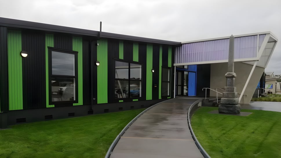 El moderno edificio verde y negro de Westland High School con camino pavimentado y área de césped.