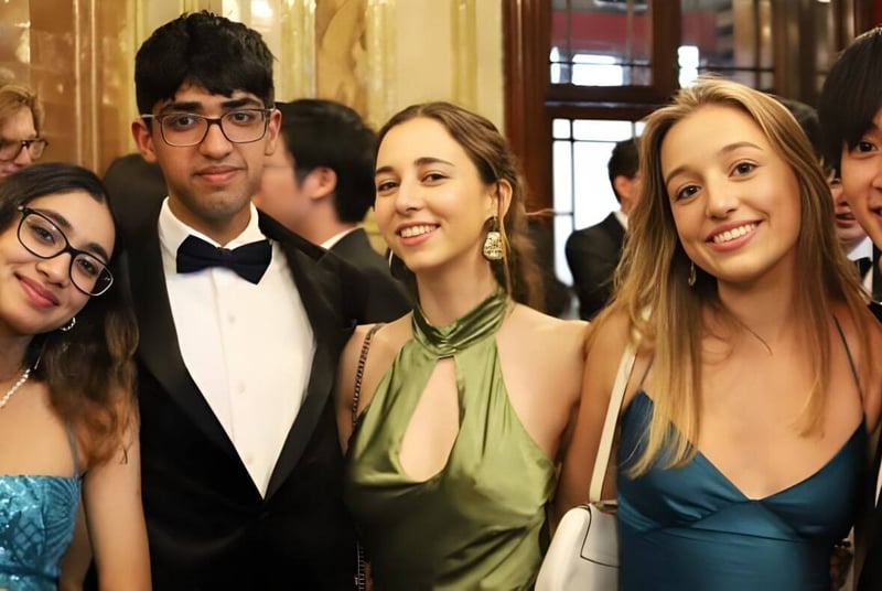 Un grupo de estudiantes de la Westminster School posan en un evento formal frente a un fondo decorativo.