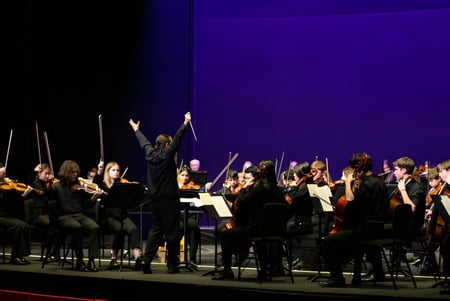 La orquesta de Westonbirt School presenta un concierto en el escenario bajo la dirección del director.