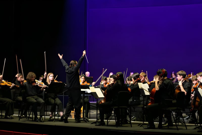 La orquesta de Westonbirt School presenta un concierto en el escenario bajo la dirección del director.