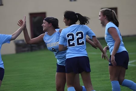 Un grupo de jóvenes deportistas está en un campo frente a edificios en el campus de la Westover School.
