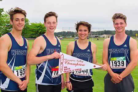 Cuatro estudiantes de la Westsyde Secondary School están al aire libre sosteniendo juntos un banner de campeonato.