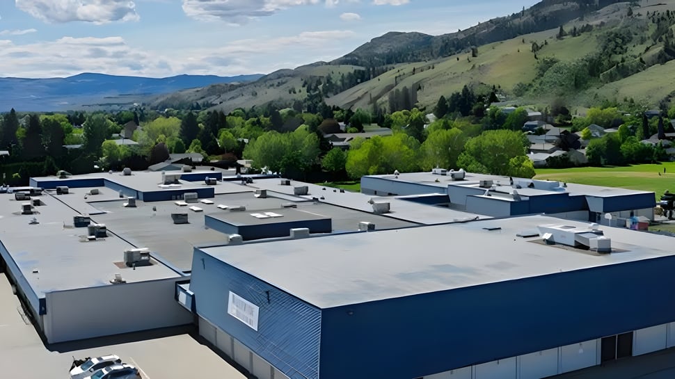 Un paisaje montañoso con una ciudad en el valle y modernos edificios azules frente a la Westsyde Secondary School.