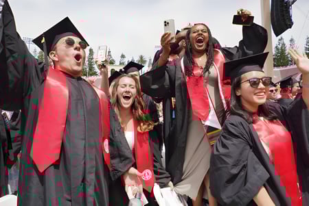 Un grupo de graduados celebra su graduación en togas negras y rojas en el campus de la Westview Freedom Academy.