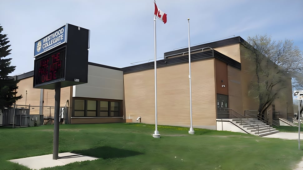 El moderno edificio de varios pisos con la bandera canadiense pertenece al Westwood Collegiate y está rodeado de césped y árboles.