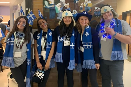 Un grupo de estudiantes de la Westwood High School está en un pasillo frente a una pared con un mural.