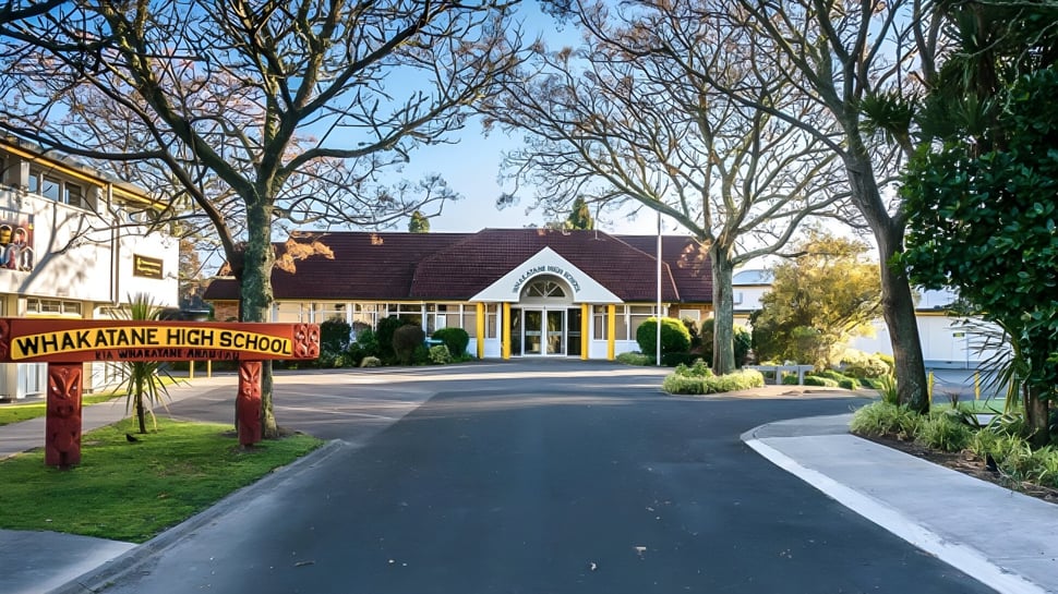 El edificio escolar de la Whakatane High School está rodeado de árboles y una entrada pavimentada.
