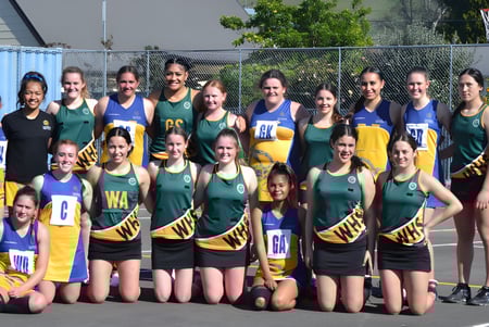 Un grupo de estudiantes del Whanganui City College posan en uniformes deportivos en un campo de baloncesto al aire libre.
