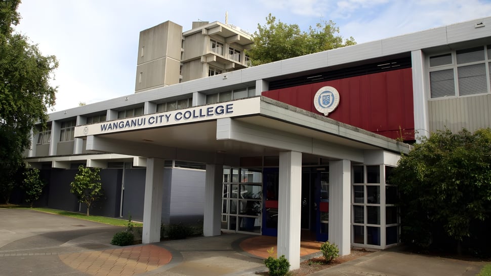 La entrada del Whanganui City College está rodeada de árboles y áreas verdes.