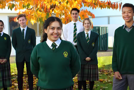 Un grupo de estudiantes de la Whanganui High School está frente al follaje otoñal.