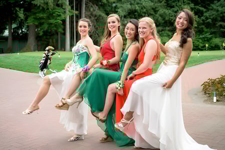 Un grupo de jóvenes mujeres en elegantes vestidos se encuentra juntas en el área exterior de la Whistler Secondary School.