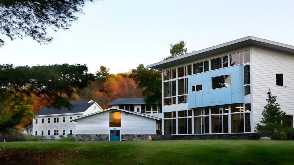 El edificio de varios pisos de la White Mountain School está rodeado de árboles con hojas de otoño.