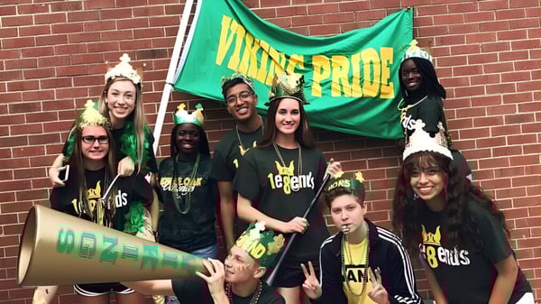 Un grupo de estudiantes de la White Oaks Secondary School está frente a una pared de ladrillos sosteniendo una bandera verde con la inscripción MAINE PRIDE.