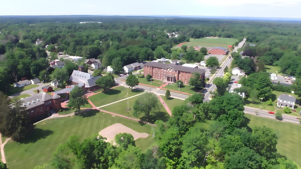 Vista aérea del extenso campus de la Wilbraham & Monson Academy con edificios históricos y modernos en el bosque verde.