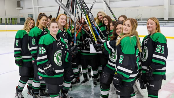 Un grupo de jugadoras de hockey de la Winchendon School en la pista de hielo con el uniforme del equipo.