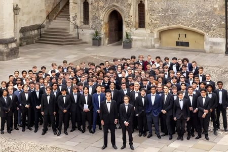 Un grupo de estudiantes en ropa formal está frente al edificio de piedra histórico del Winchester College.