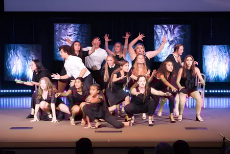 Estudiantes de la Windermere Preparatory School realizan una dinámica presentación de baile en el escenario con iluminación colorida.