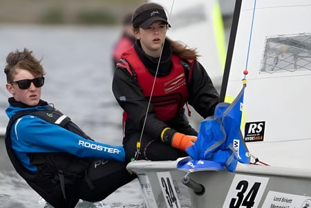 Dos personas están al lado de un vehículo con el logo de Gallo en el terreno de la Windermere School.