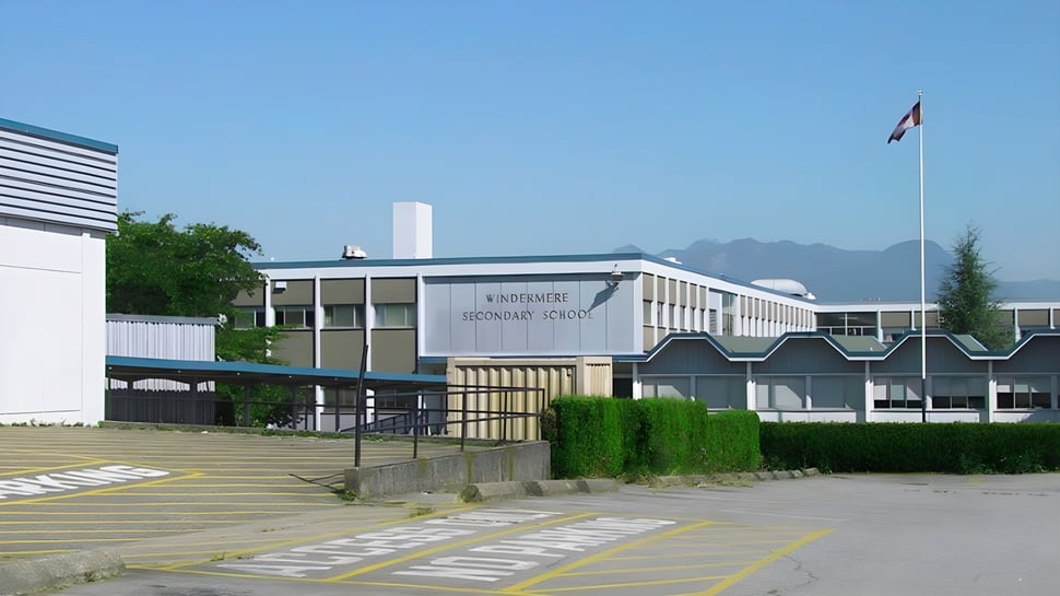 El moderno edificio de varios pisos de la Windermere Secondary School con una bandera suiza ondeando en primer plano.