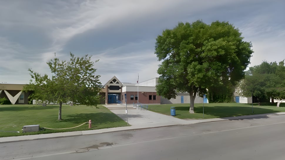 El colorido edificio con techo triangular en el campus de la Winston Churchill High School está rodeado de árboles y una zona verde.